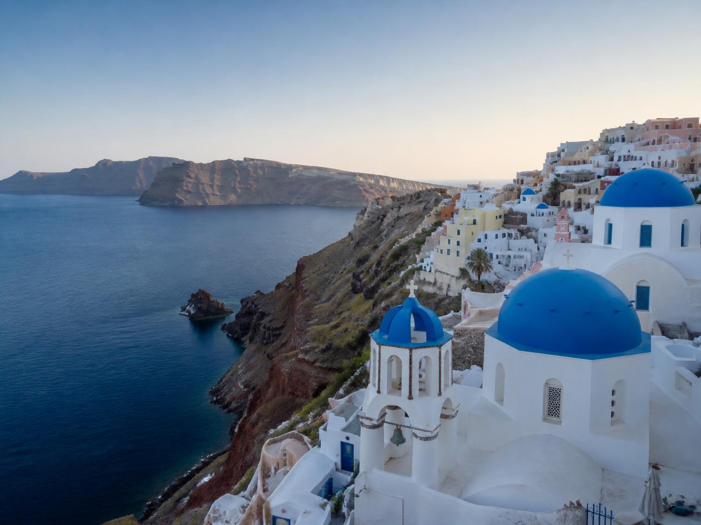Whitewashed houses and blue church domes on the caldera cliffs of Oia, Santorini, Greece
