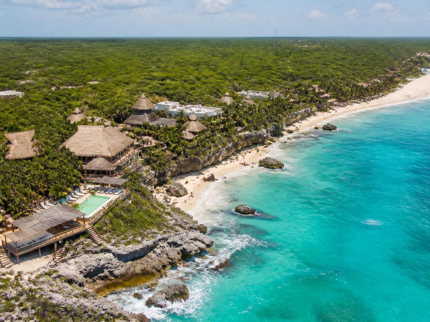 Aerial view of the Riviera Maya coastline near Tulum, Mexico, with jungle, white limestone beach, and turquoise Caribbean water