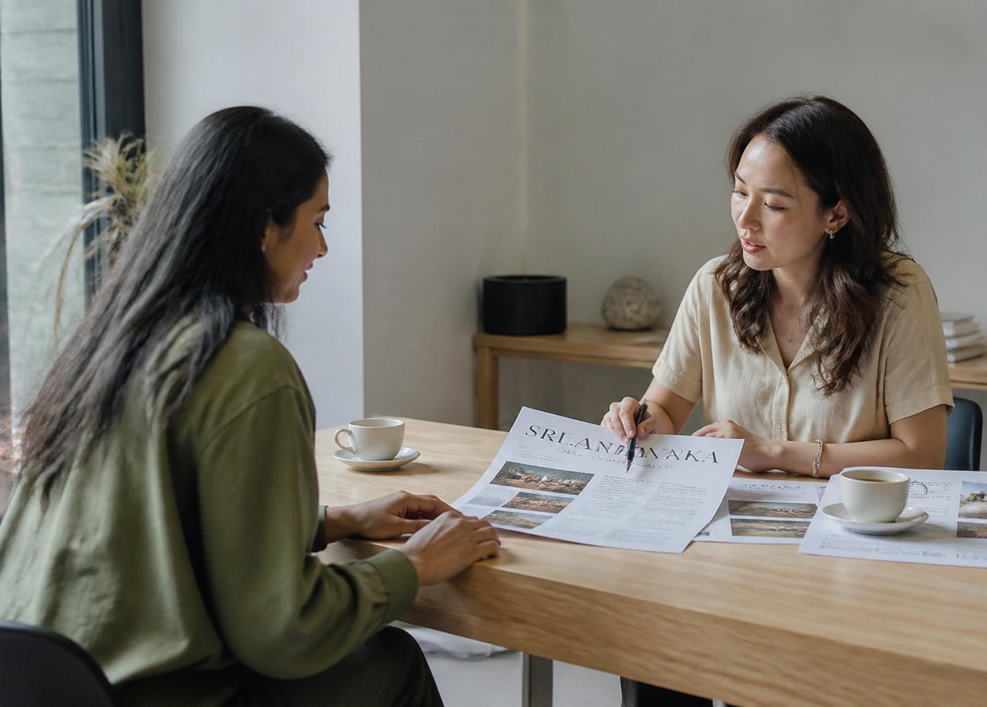 A traveler consults with an advisor at a serene table, an itinerary between them in natural window light